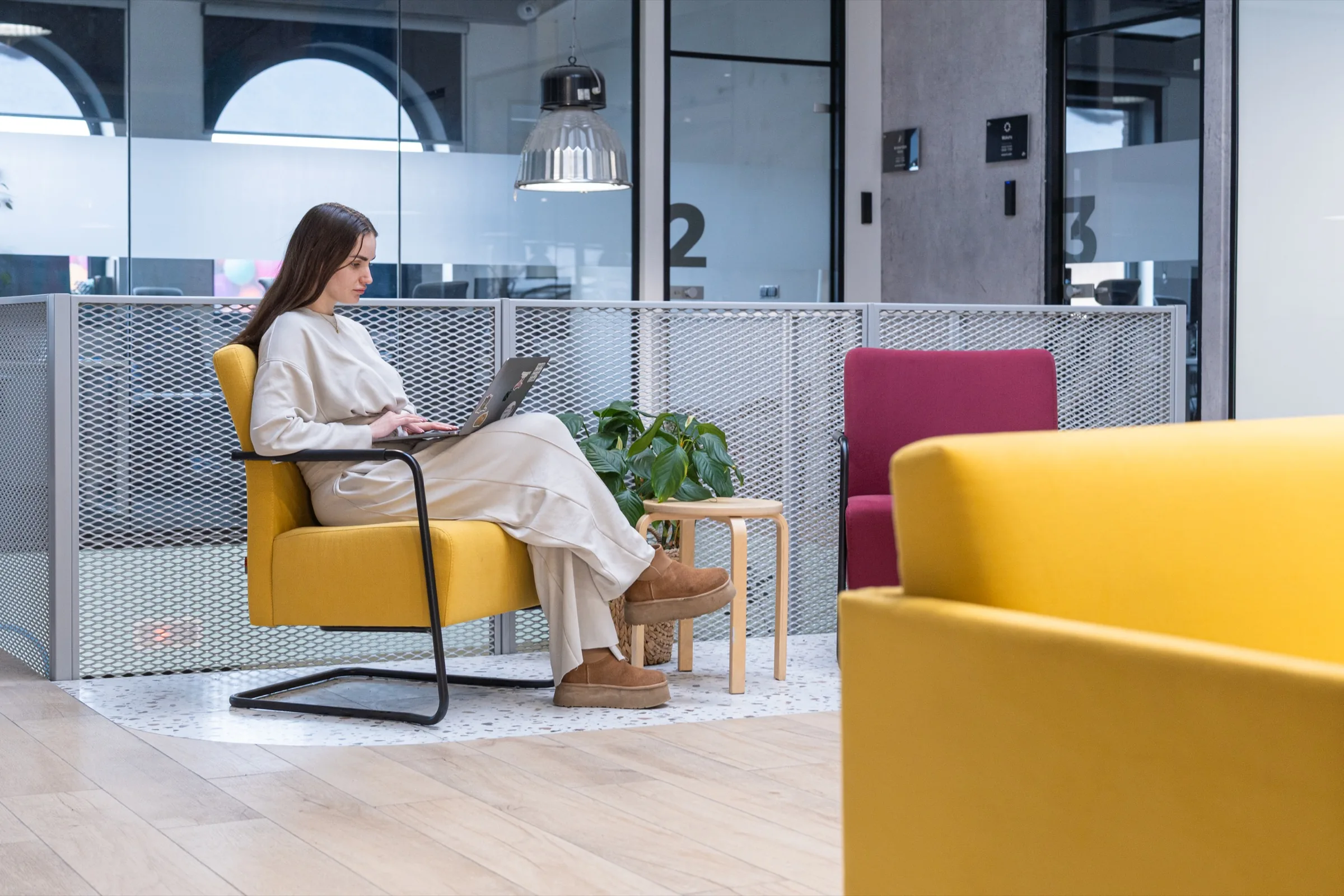 A member working from a yellow chair on Floor 1 at Kolodvorska